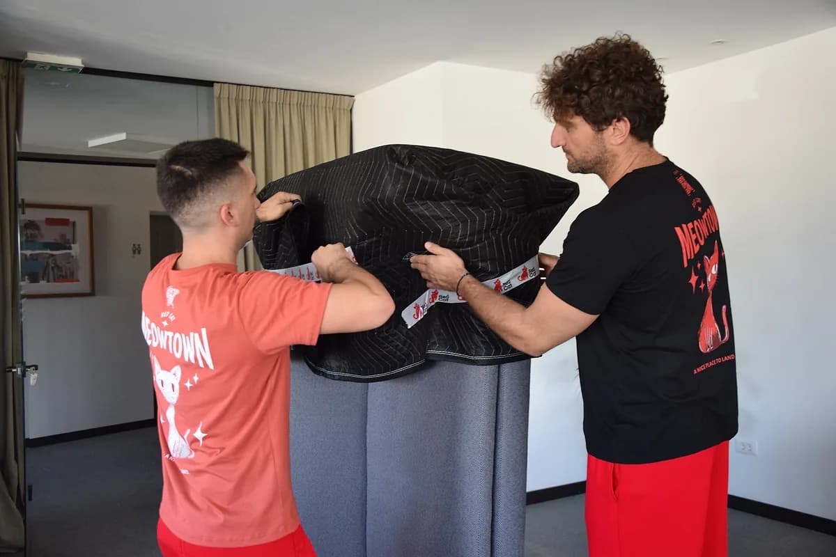 Two Red Cat apartment movers blanket-wrapping a piece of furniture