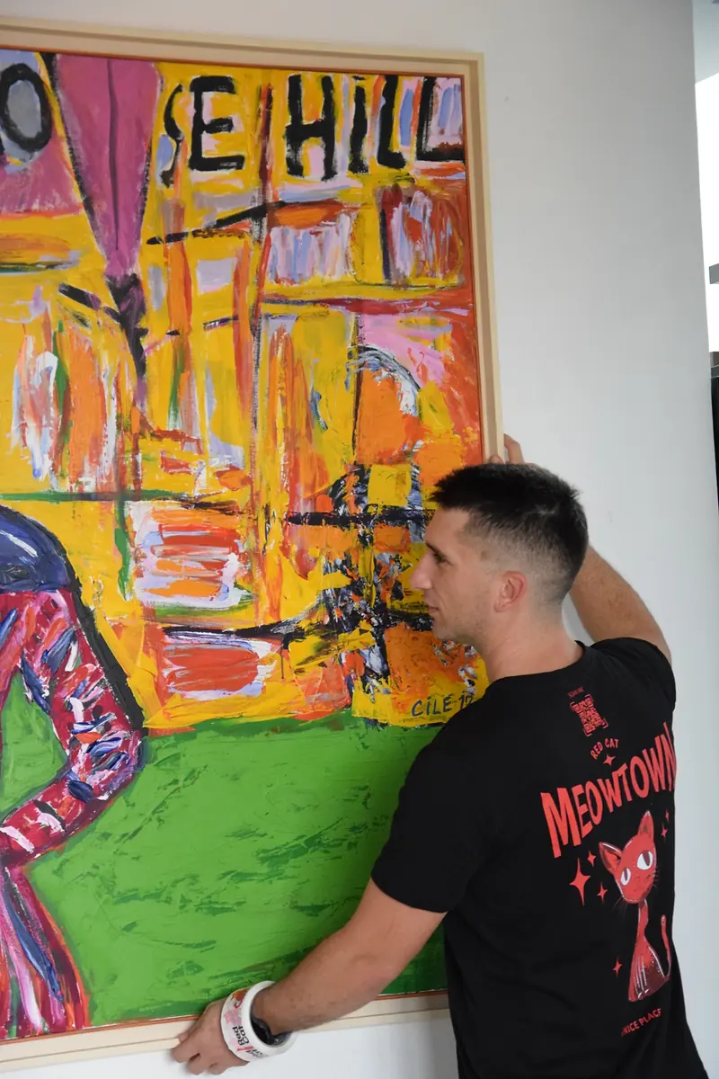 Red Cat apartment mover hanging a large painting