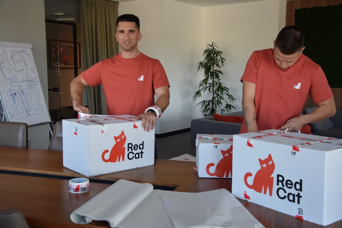 Two Red Cat business movers packing Red Cat boxes in a conference room