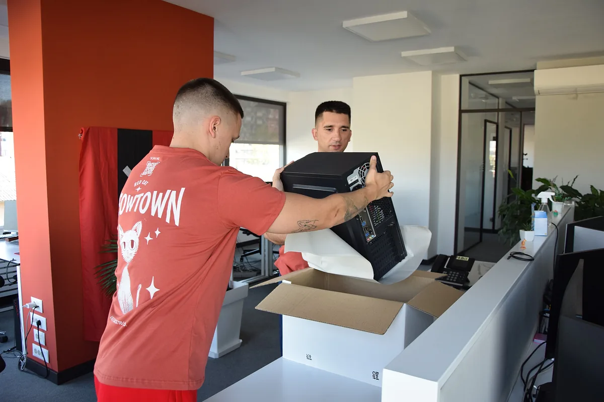 Red Cat movers boxing a computer at the office reception desk