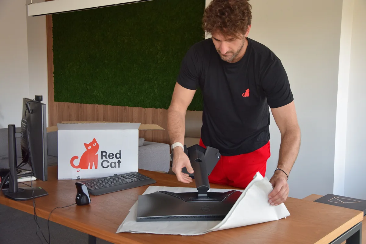 Red Cat corporate relocation mover wrapping a monitor at an office desk