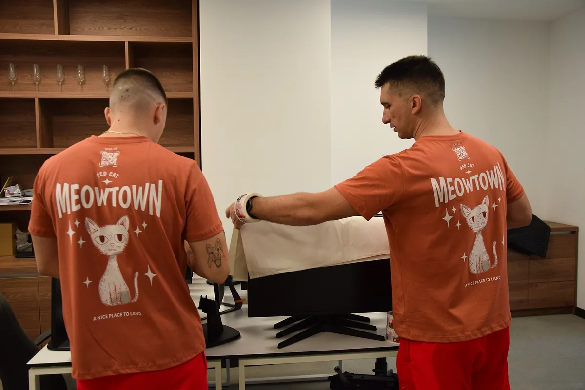 Two Red Cat movers wrapping an office monitor