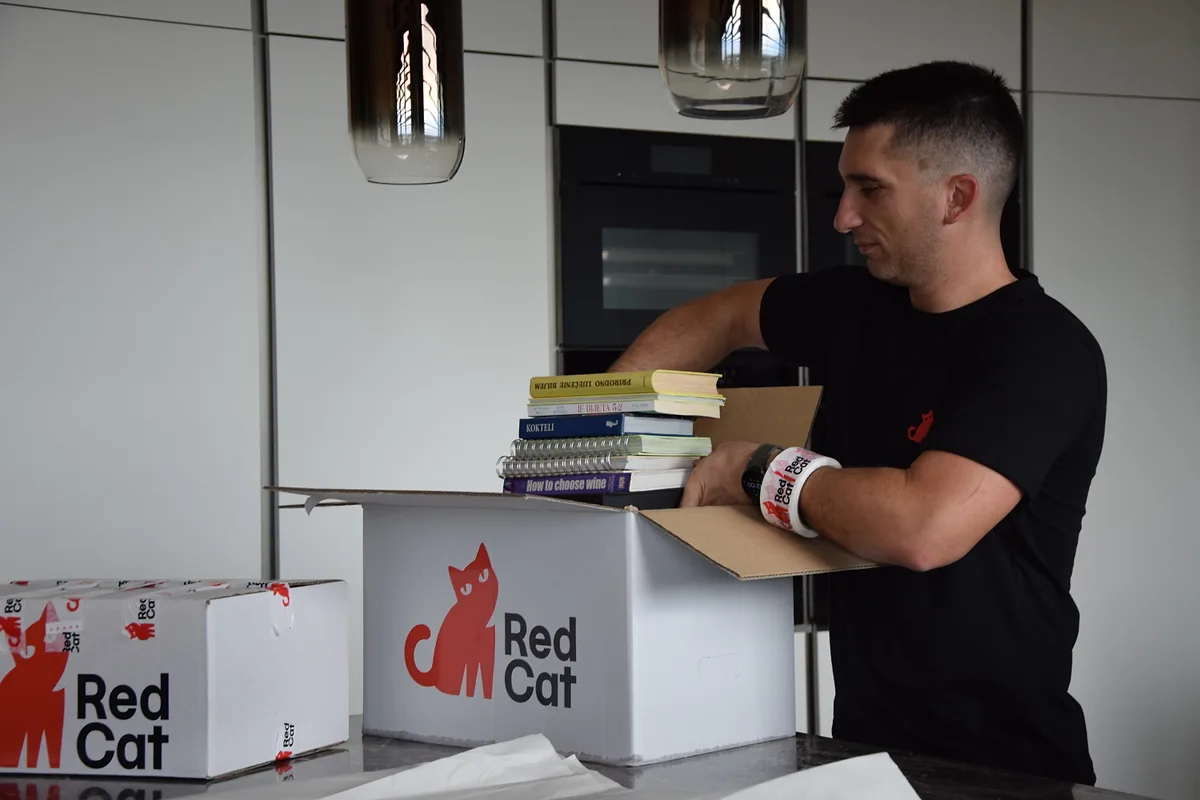 Red Cat mover packing books into a Red Cat box in the kitchen