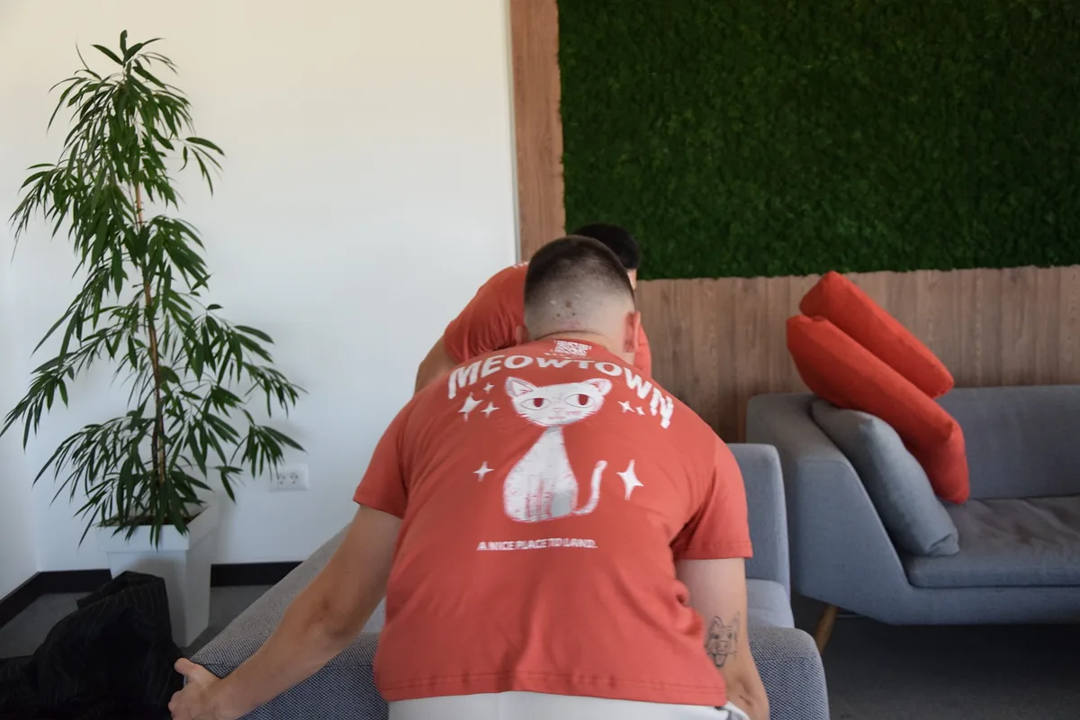 Red Cat furniture delivery movers placing a sofa in a lounge