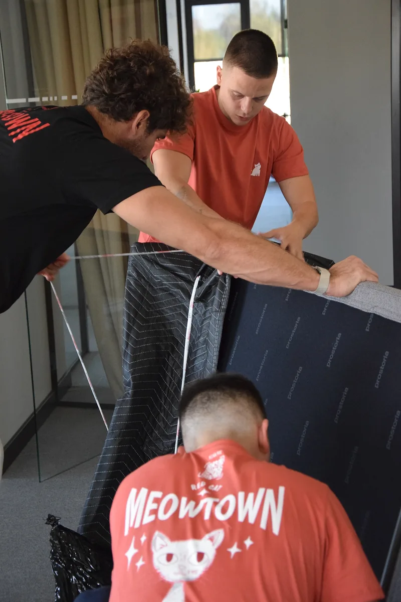 Red Cat furniture delivery movers wrapping a sofa in moving blankets