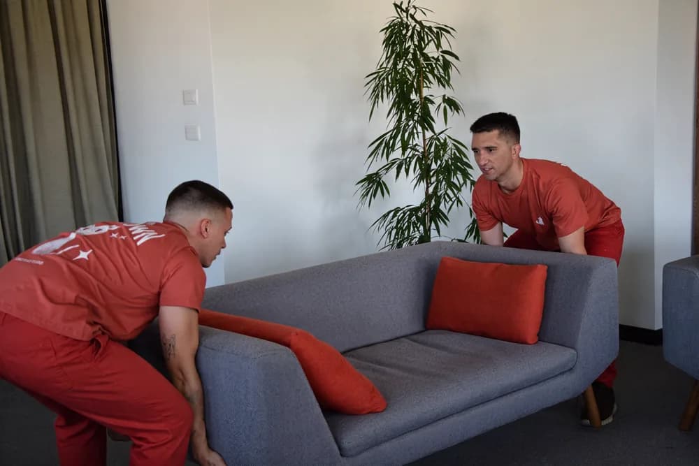 Two Red Cat movers setting down a sofa