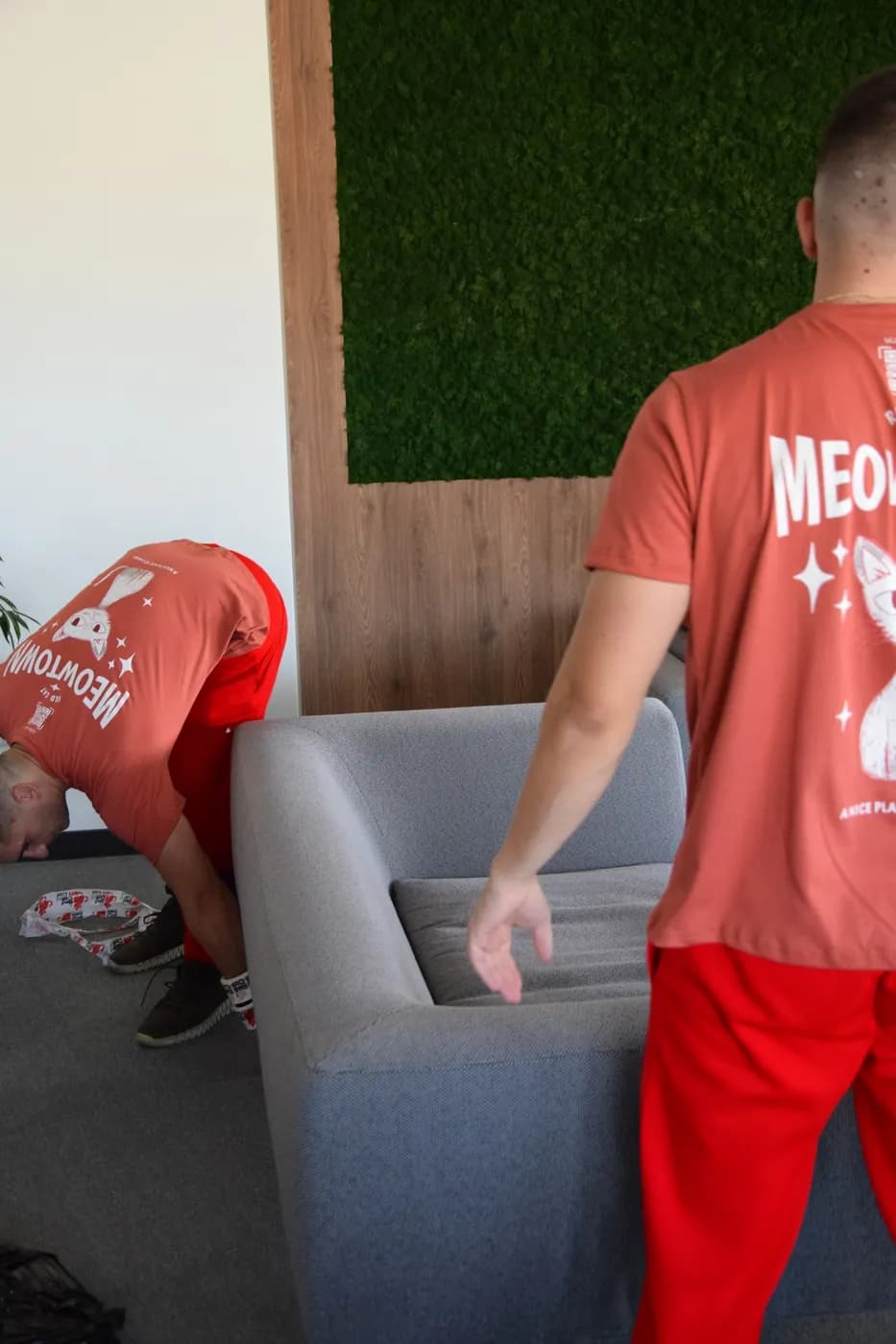 Two Red Cat movers getting ready to lift a grey sofa