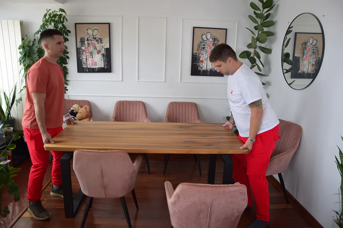 Two Red Cat labor-only movers carrying a wooden dining table