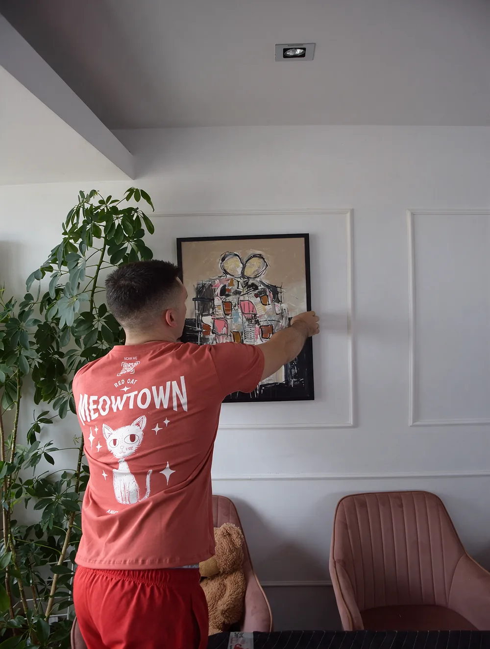 Red Cat mover hanging a painting in Sarah's new Bethesda apartment