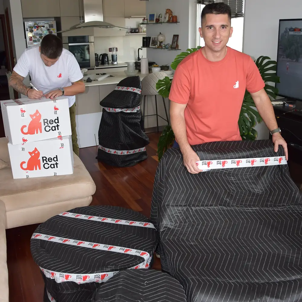 Red Cat local movers wrapping furniture in moving blankets in a living room