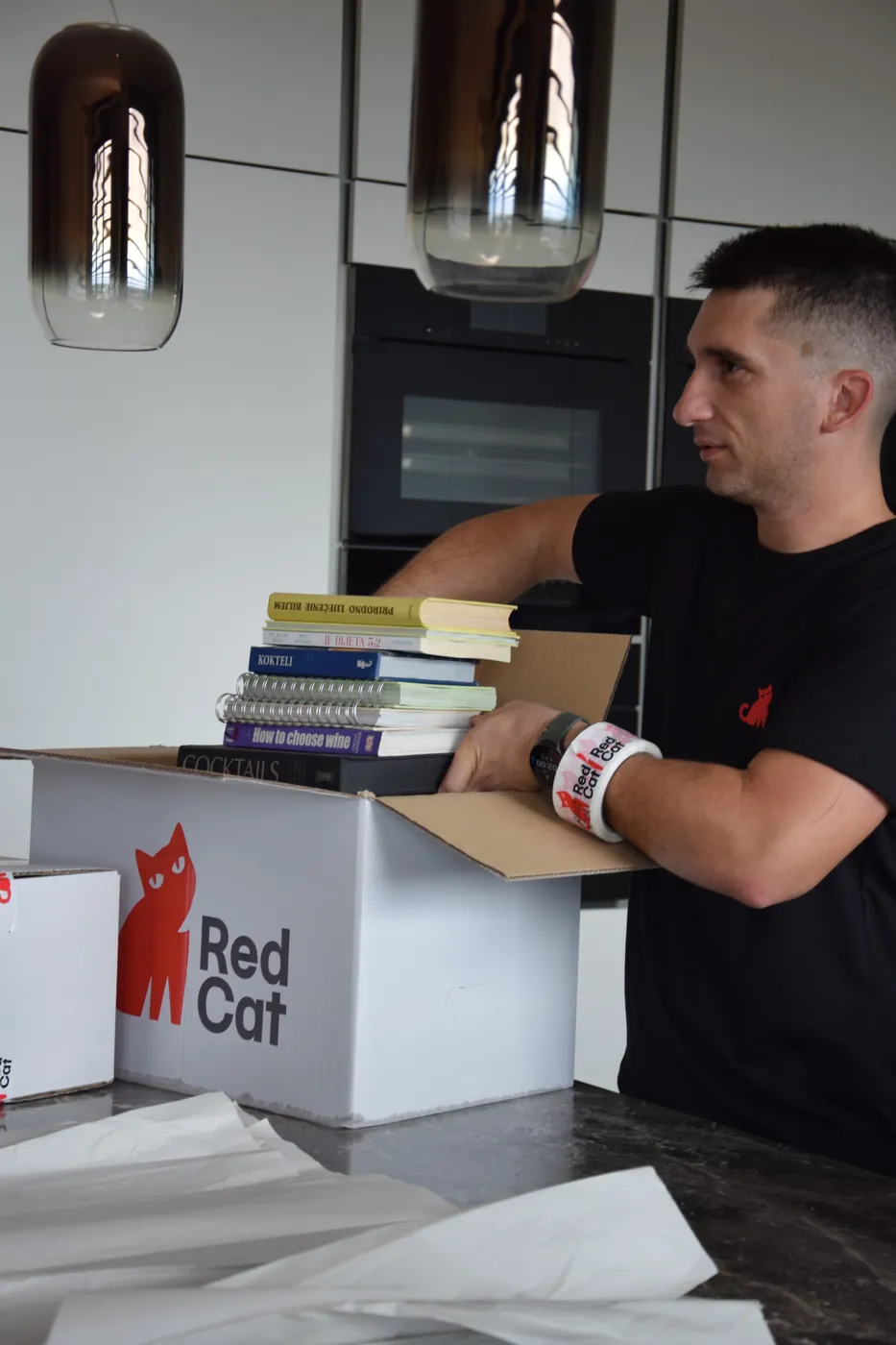 Red Cat mover packing books into a Red Cat box in a modern kitchen