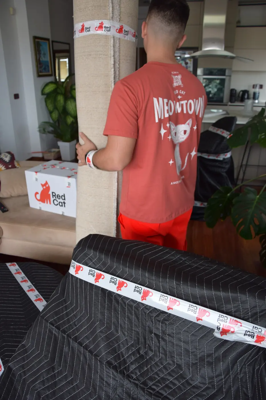 Red Cat mover in a living room with blanket-wrapped furniture and a Red Cat box