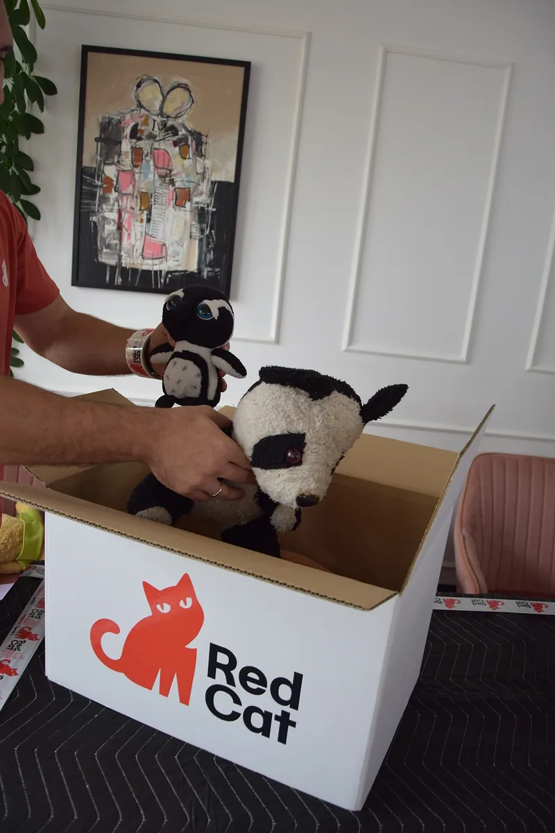 Red Cat packer packing stuffed toys into a Red Cat box