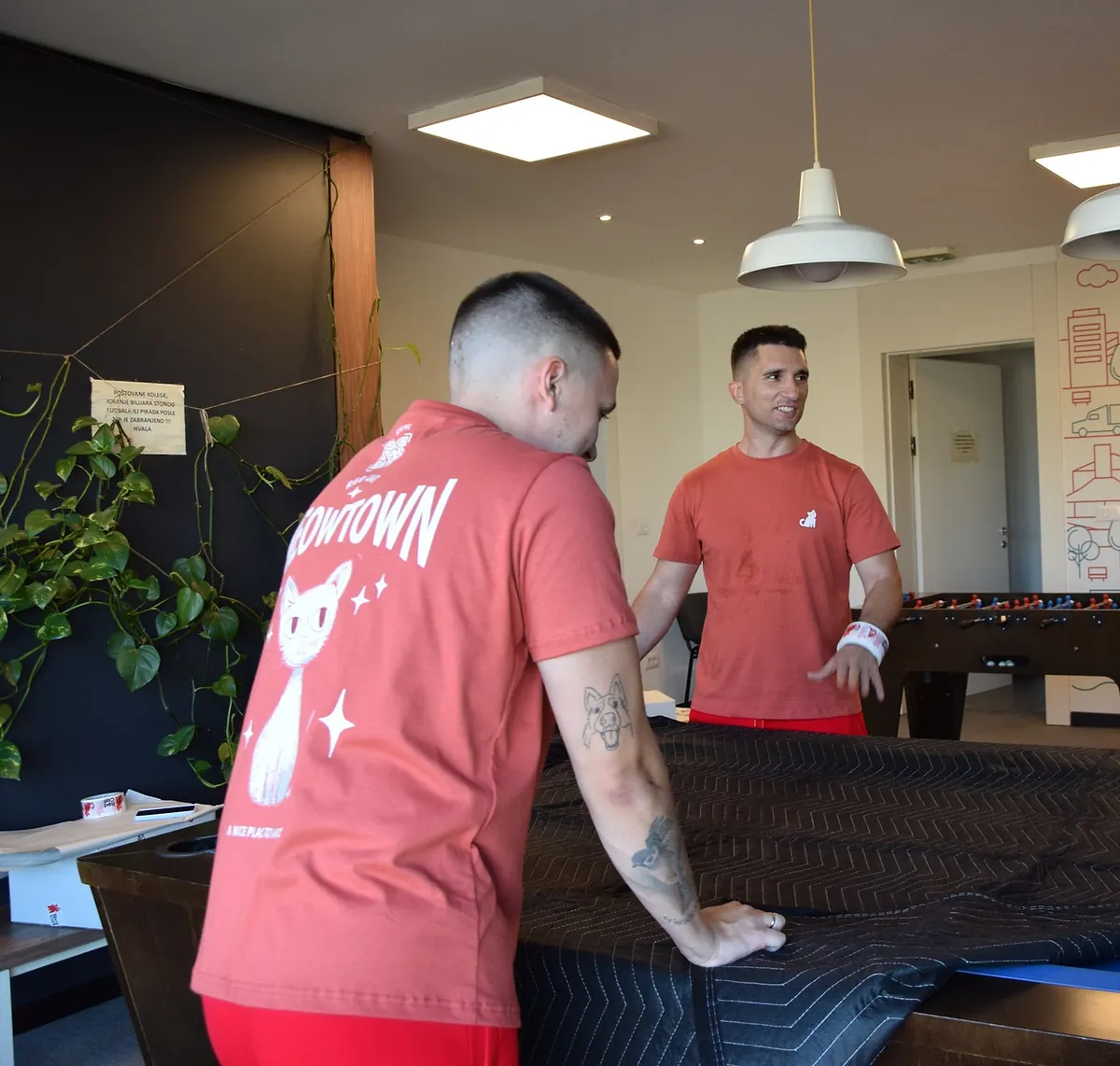 Red Cat movers covering a heavy piece with a moving blanket