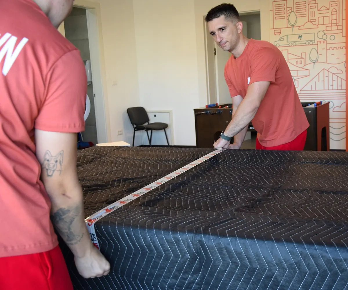 Red Cat movers taping a blanket wrap tight