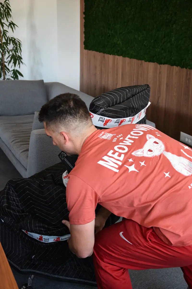 A Red Cat mover wrapping a chair in moving blankets