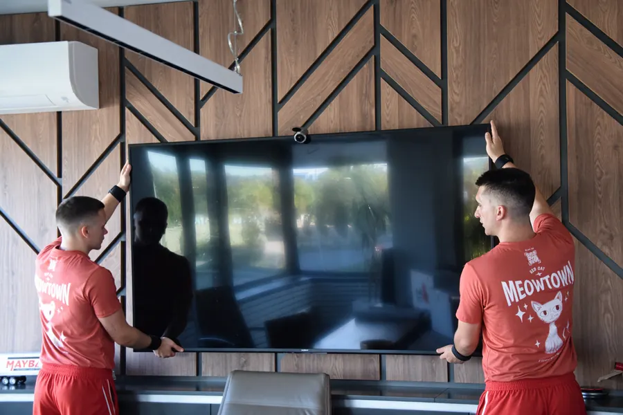 Red Cat movers taking a wall-mounted TV down