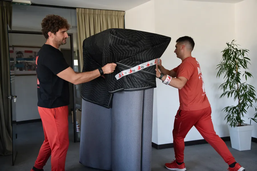 Red Cat movers wrapping furniture in moving blankets and Red Cat tape