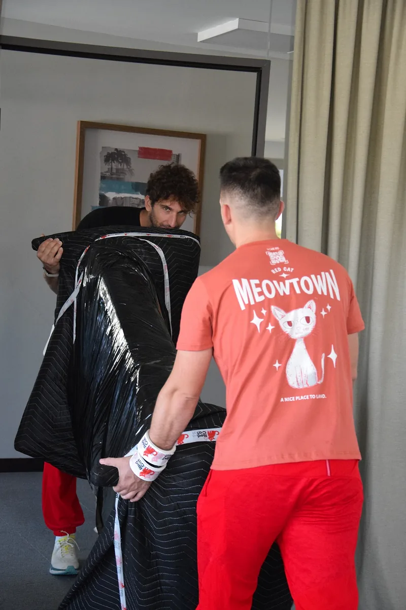 Two Red Cat same day movers carrying blanket-wrapped furniture
