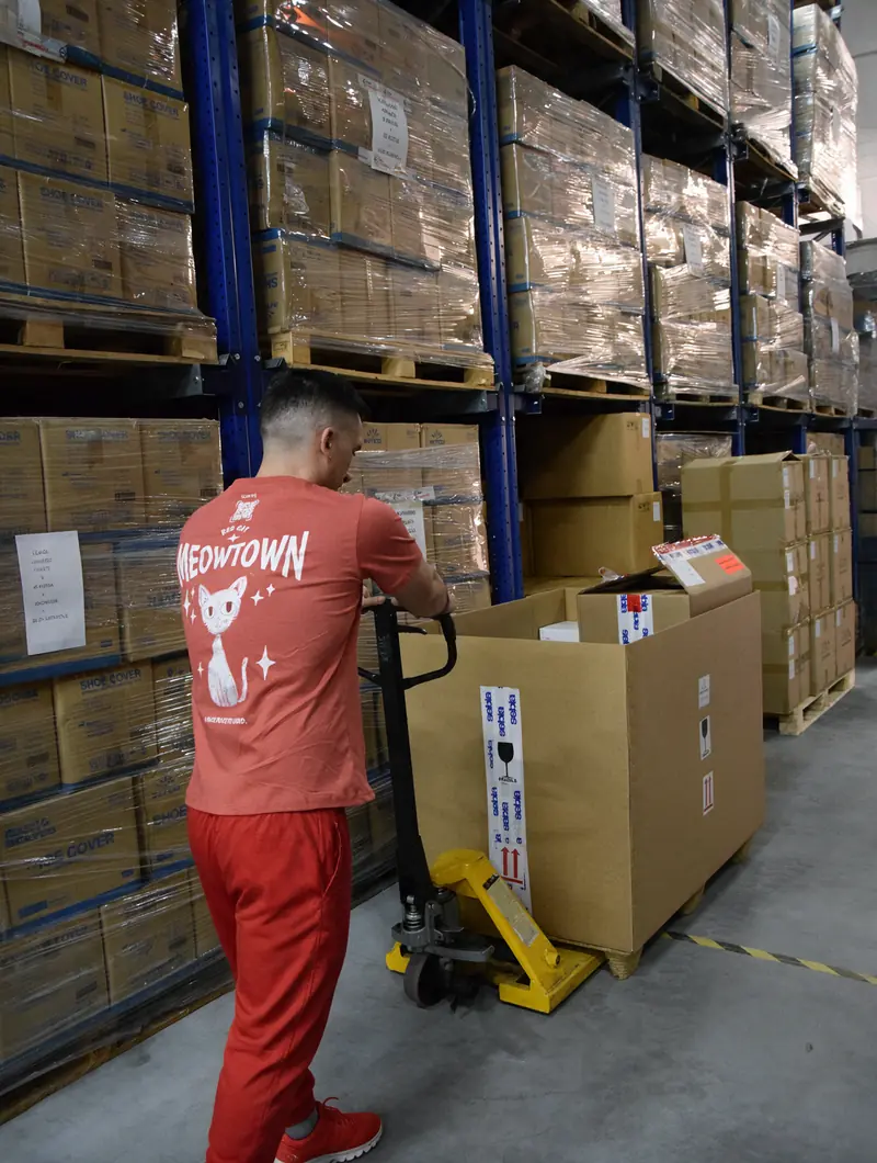 A Red Cat mover moving a pallet with a pallet jack