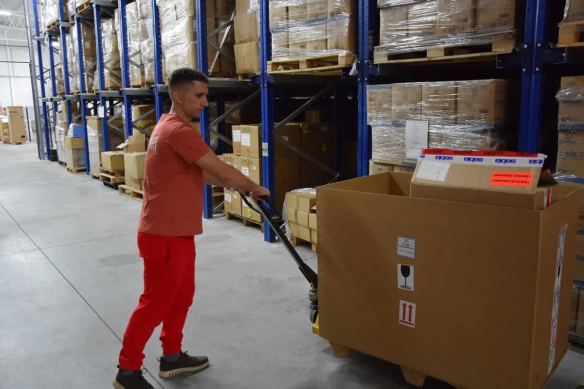 Red Cat warehouse mover pushing a loaded pallet jack down a warehouse aisle