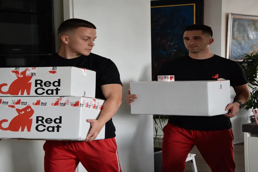 Red Cat movers carrying moving boxes