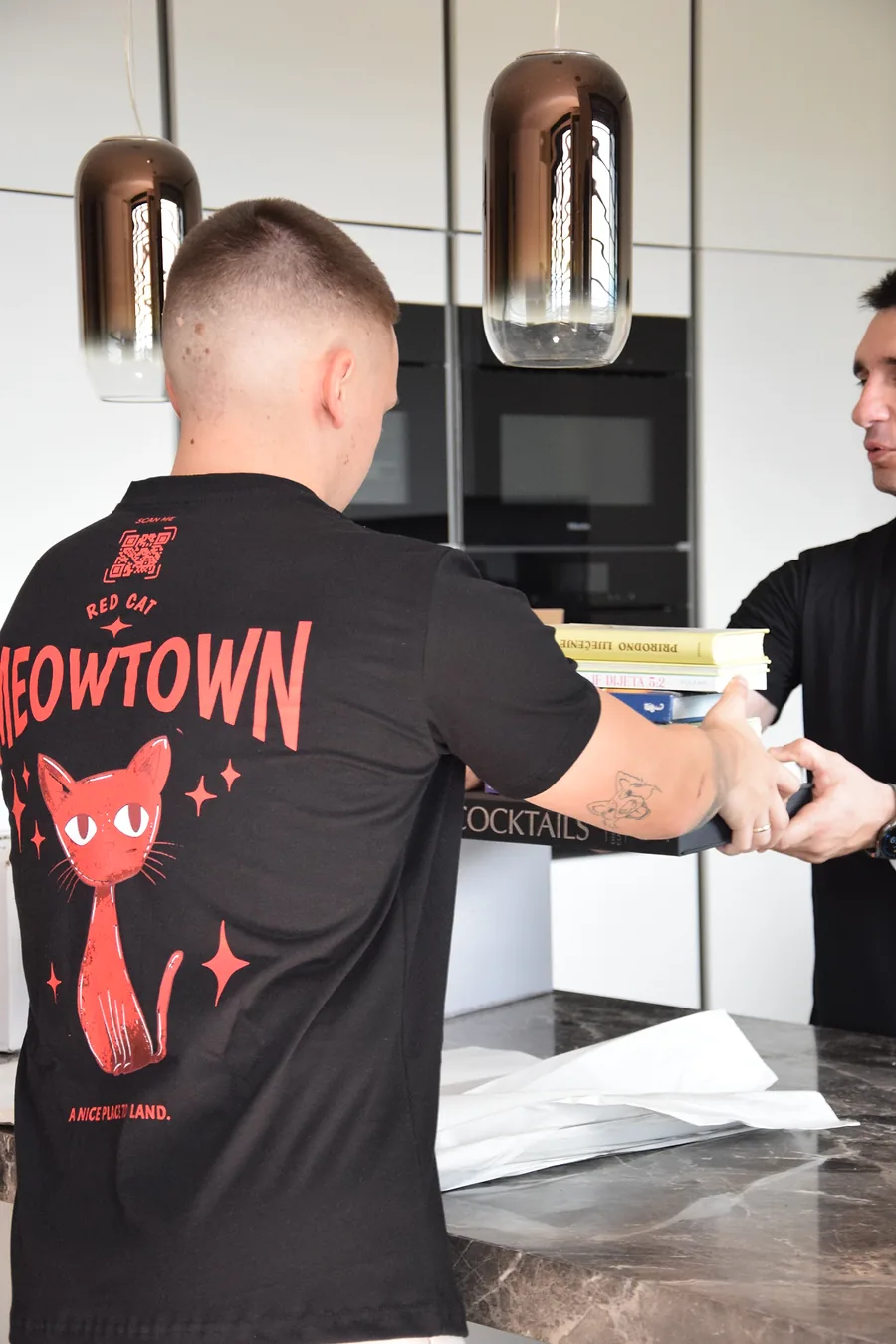 Red Cat white glove movers handing books across a kitchen island to pack