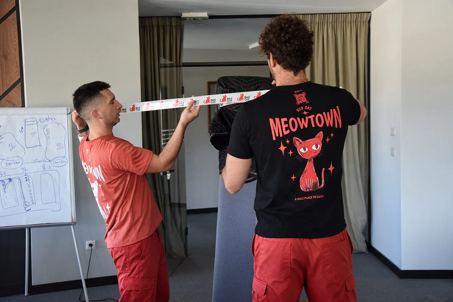 Red Cat white glove movers taping a blanket-wrapped piece of furniture